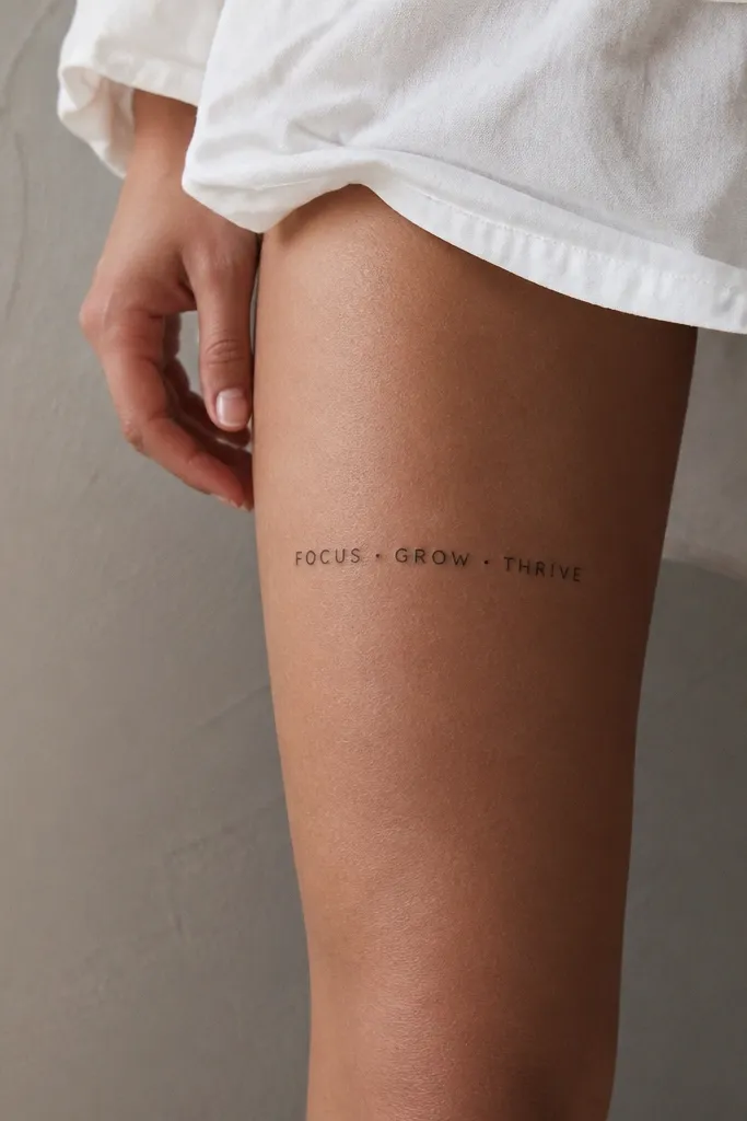 A short phrase above the knee with small black dots separating each word. The letters are minimal uppercase, dots are evenly sized, no other decoration.