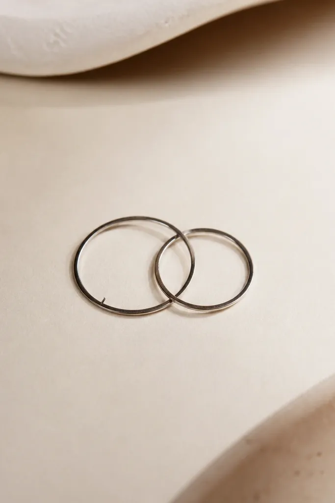 Two interlocking circles drawn in fine black. One circle has a single straight micro line across it like a tiny engraved mark.