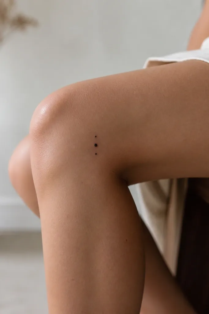 Three tiny black dots arranged in a short vertical line on the outer side of the knee, with the middle dot slightly larger.
