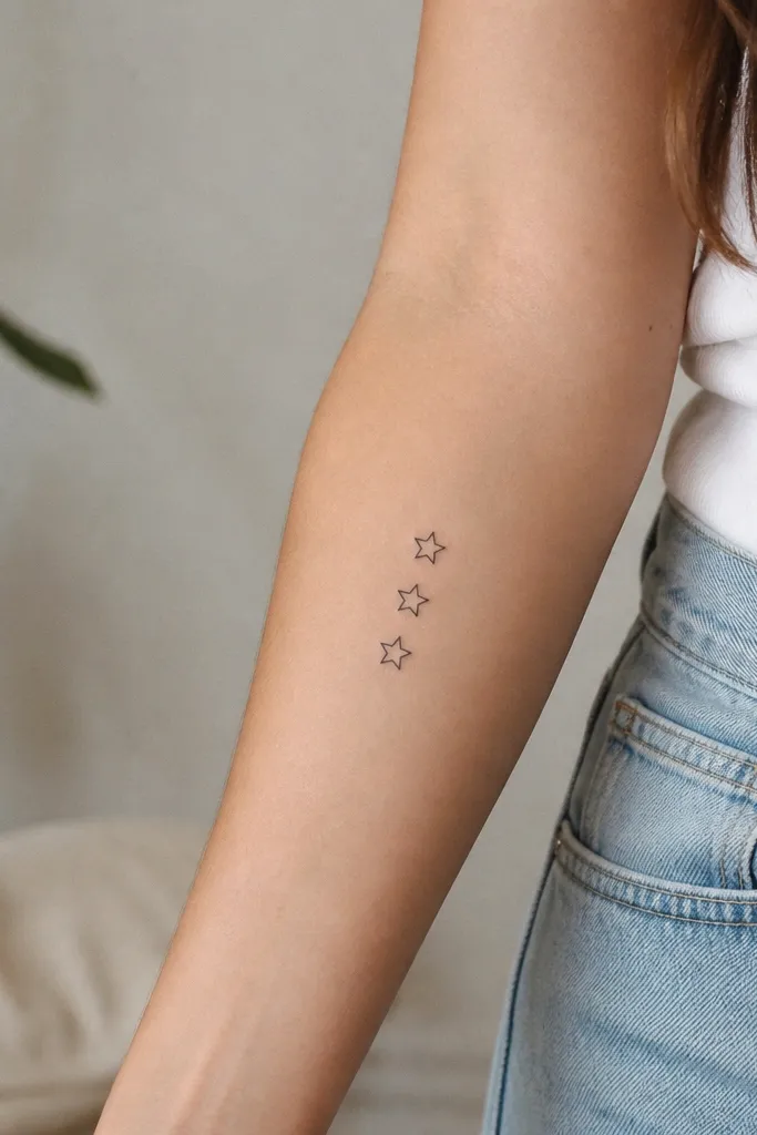 Three small five-point stars stacked vertically, each outlined in black with no fill, on the inner forearm.
