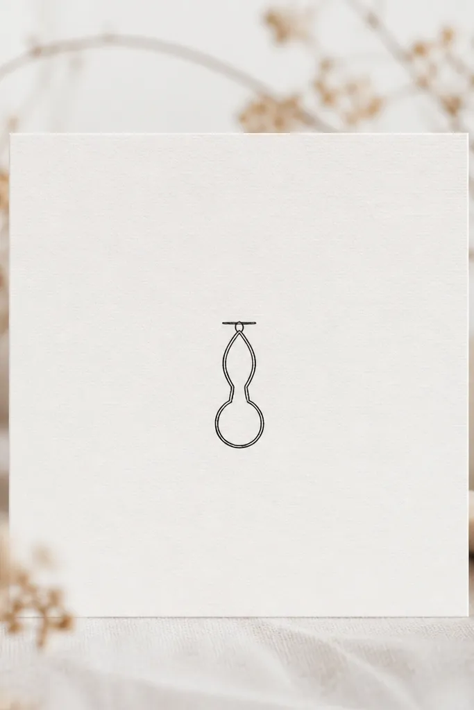 A small vertical keyhole pendant in thin black ink. The top is a narrow teardrop opening, and the bottom is a rounded keyhole shape. There's a short horizontal line at the top as the "chain" connector.