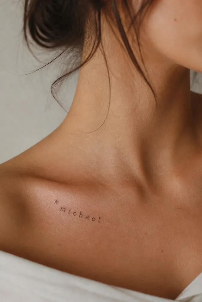 A collarbone tattoo: the partner name in small fine serif letters, starting with a single five-point star, with the rest of the name hanging beneath it in a slight downward slope.
