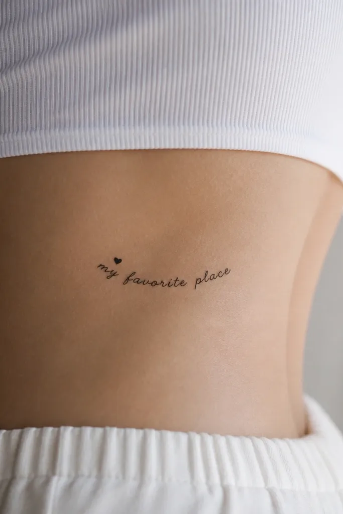A small script phrase reading "my favorite place" with all lowercase. Above the first word is a tiny heart outline filled in solid black, and the phrase is centered below it. The baseline follows the waist curve.